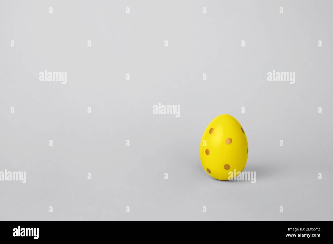 Trendy colorful Easter yellow egg on a gray background with copy space. Minimalism greeting card concept. Stock Photo