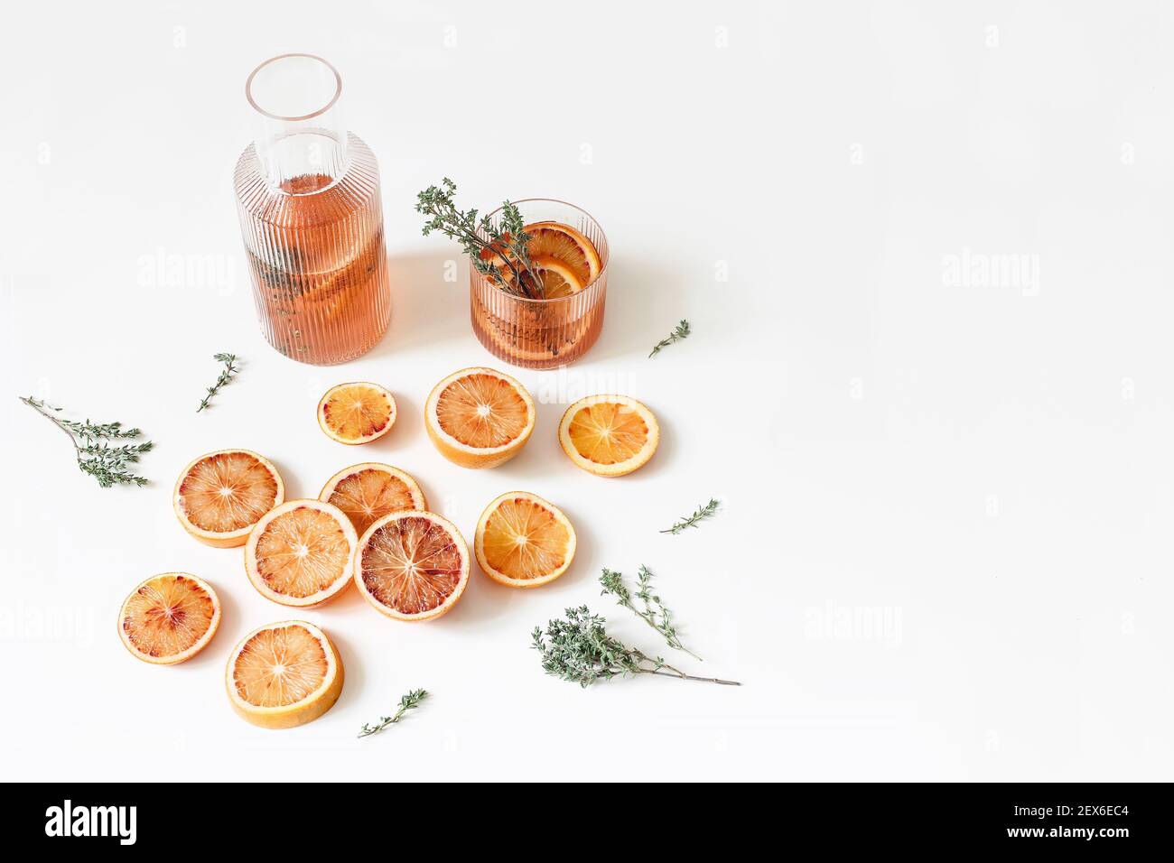 Fresh blood oranges pattern. Whole and cut fruits with thyme herb isolated on white table backgrounds. Lemonade drink, cocktail in glass caraffe. Food Stock Photo
