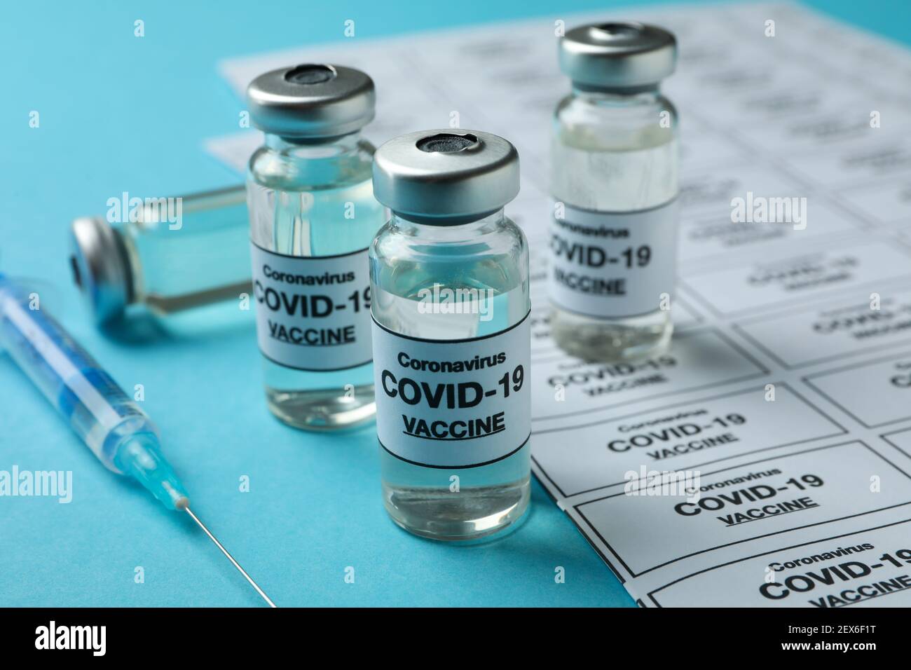 Concept of Covid - 19 vaccination with vials and syringe on blue ...