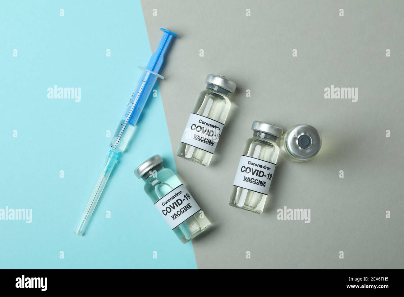 Vials of Covid - 19 vaccine and syringe on two tone background Stock ...