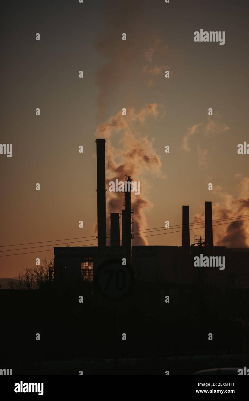 Silhouette of industrial chimneys with smoke in sunset Stock Photo - Alamy