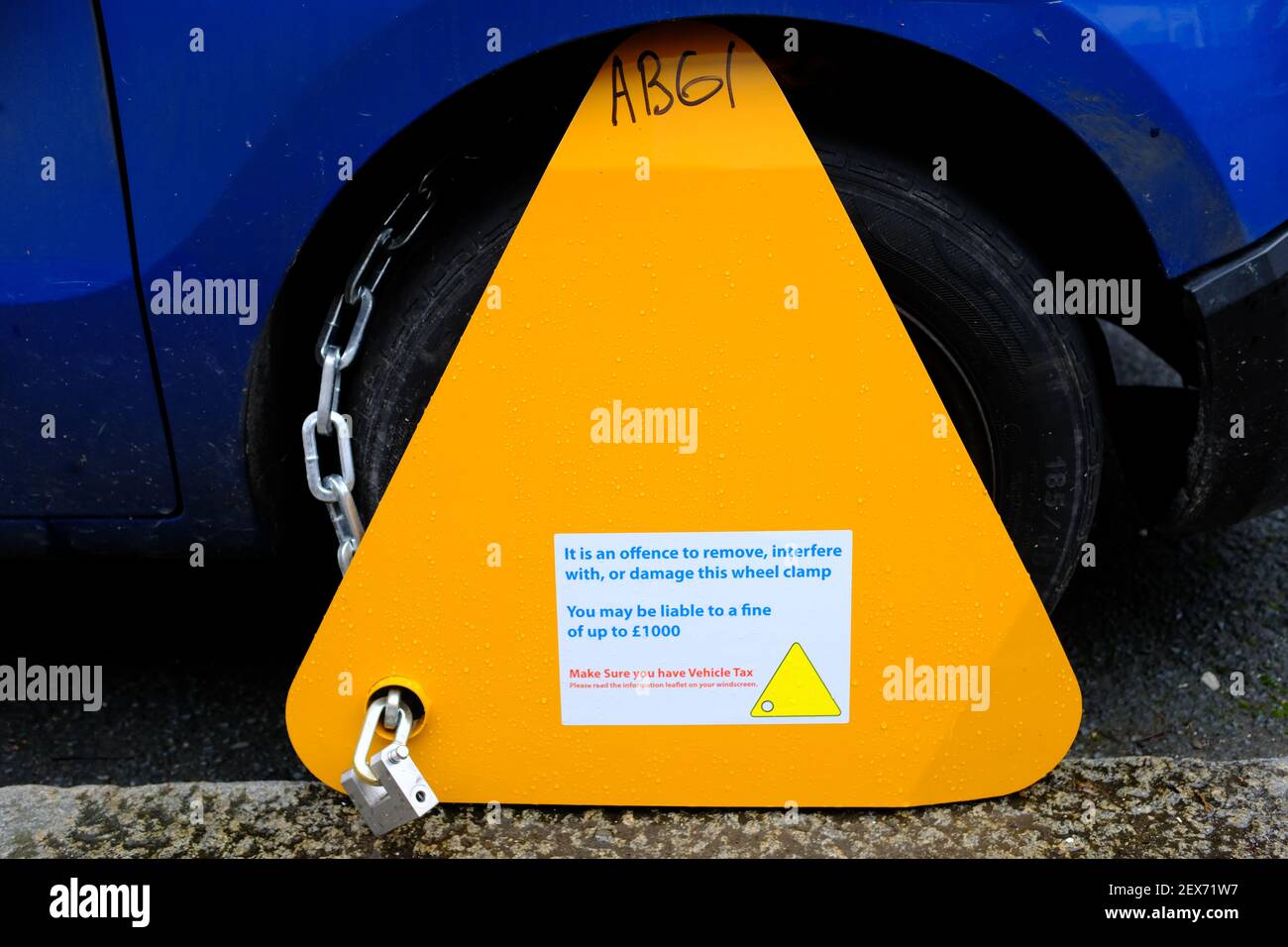LONDON - 4TH MARCH 2021: A yellow wheel clamp on a blue van. The result of not paying your vehicle tax. Stock Photo