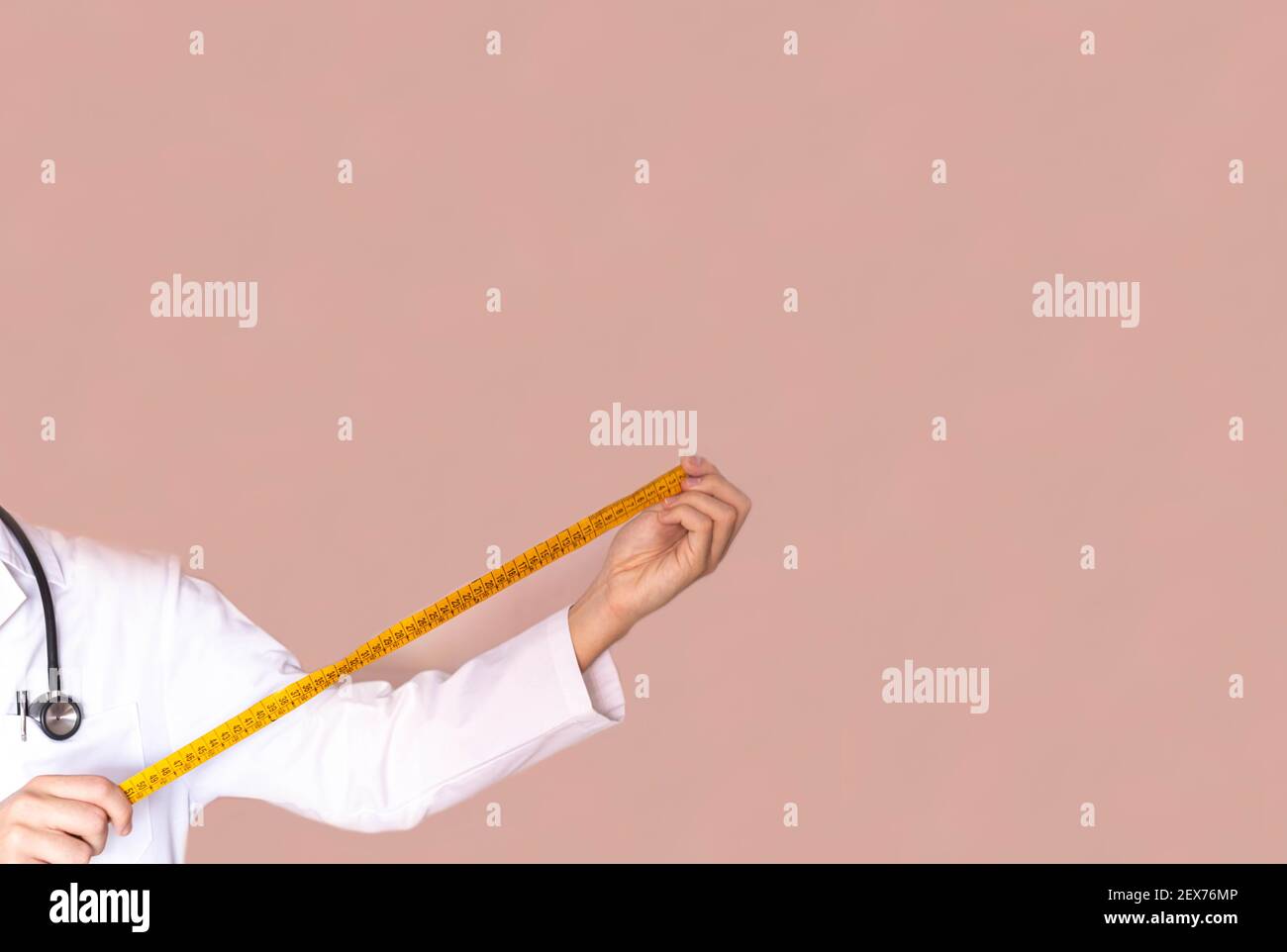 selective focus of an endocrine doctor and nutritionist holding a measuring tape to check the weight and measurement of his patients health concept Stock Photo