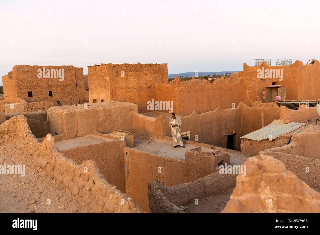 Morocco, Tinejdad, Todra Valley, Ksar El Khorbat, is a village of  fortified walls made of soil, lone man on roof top Stock Photo