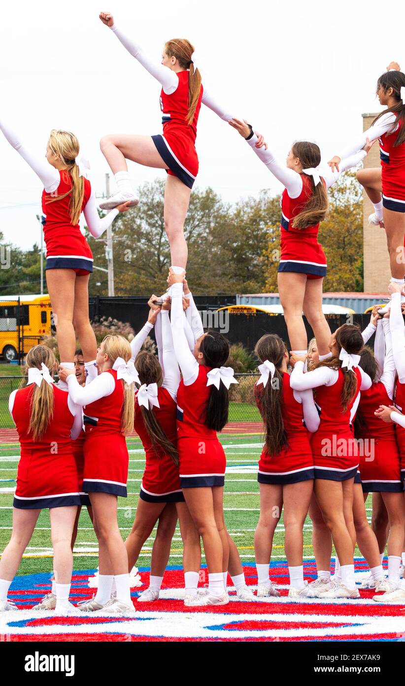 West Islip, New York, USA - 11 October 2019: High school cheerleaders cheering at half time of a football game in the middle of the field holding each Stock Photo