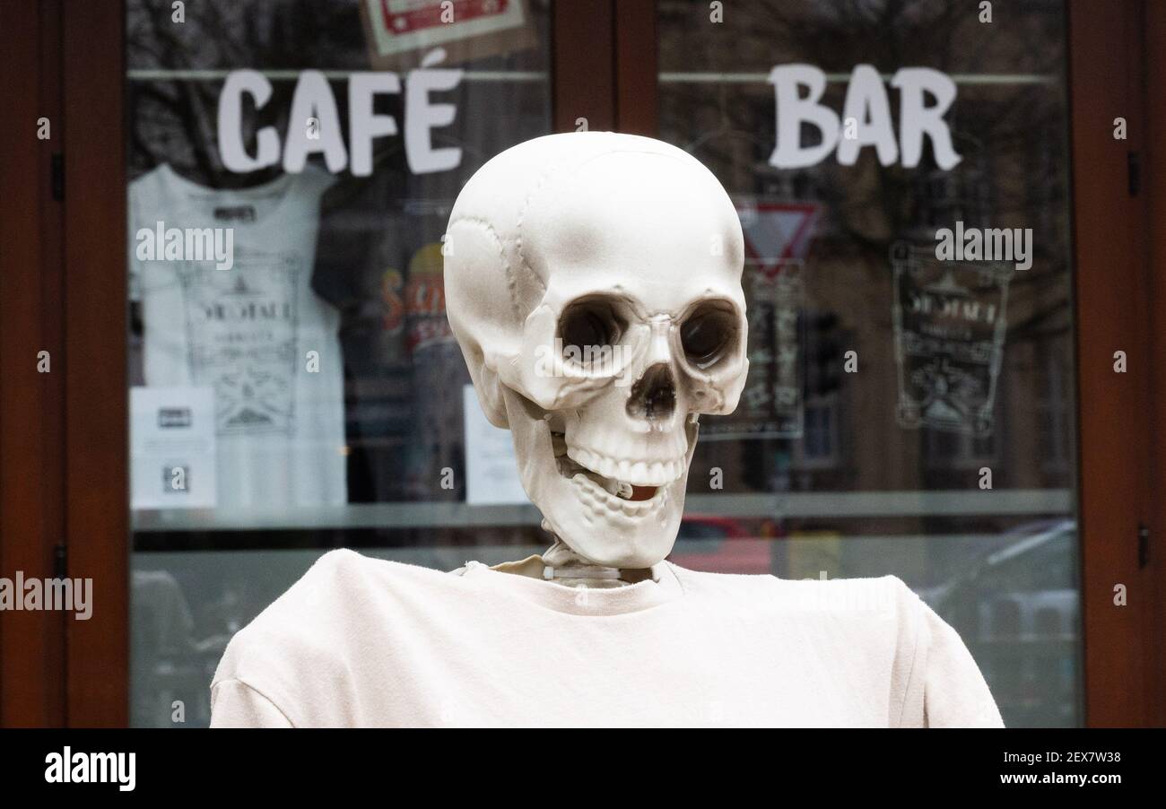 04 March 2021, Lower Saxony, Hanover: A skeleton sits outside a restaurant closed due to the Corona pandemic in Südstadt. The lockdown in Germany is extended until March 28. Photo: Julian Stratenschulte/dpa Stock Photo