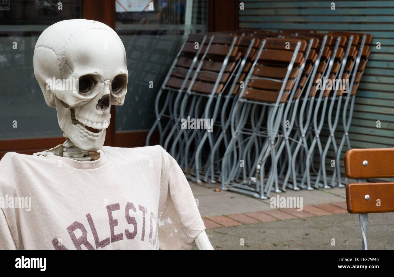 04 March 2021, Lower Saxony, Hanover: A skeleton sits outside a restaurant closed due to the Corona pandemic in Südstadt. The lockdown in Germany is extended until March 28. Photo: Julian Stratenschulte/dpa Stock Photo