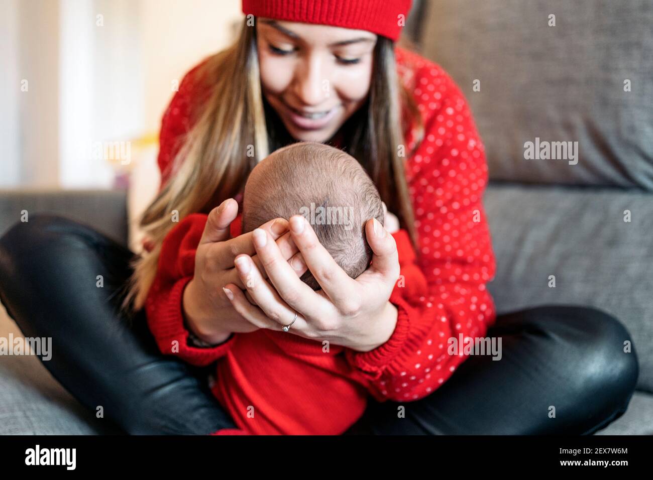 Stock photo of adorable mother holding her baby in the couch. Stock Photo