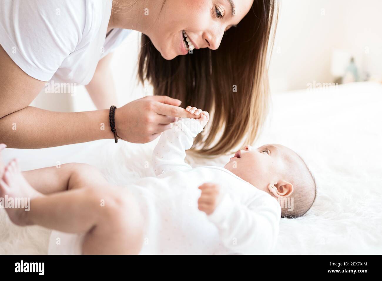 Stock photo of young mother sharing cute moment with her little baby lying in the bed Stock