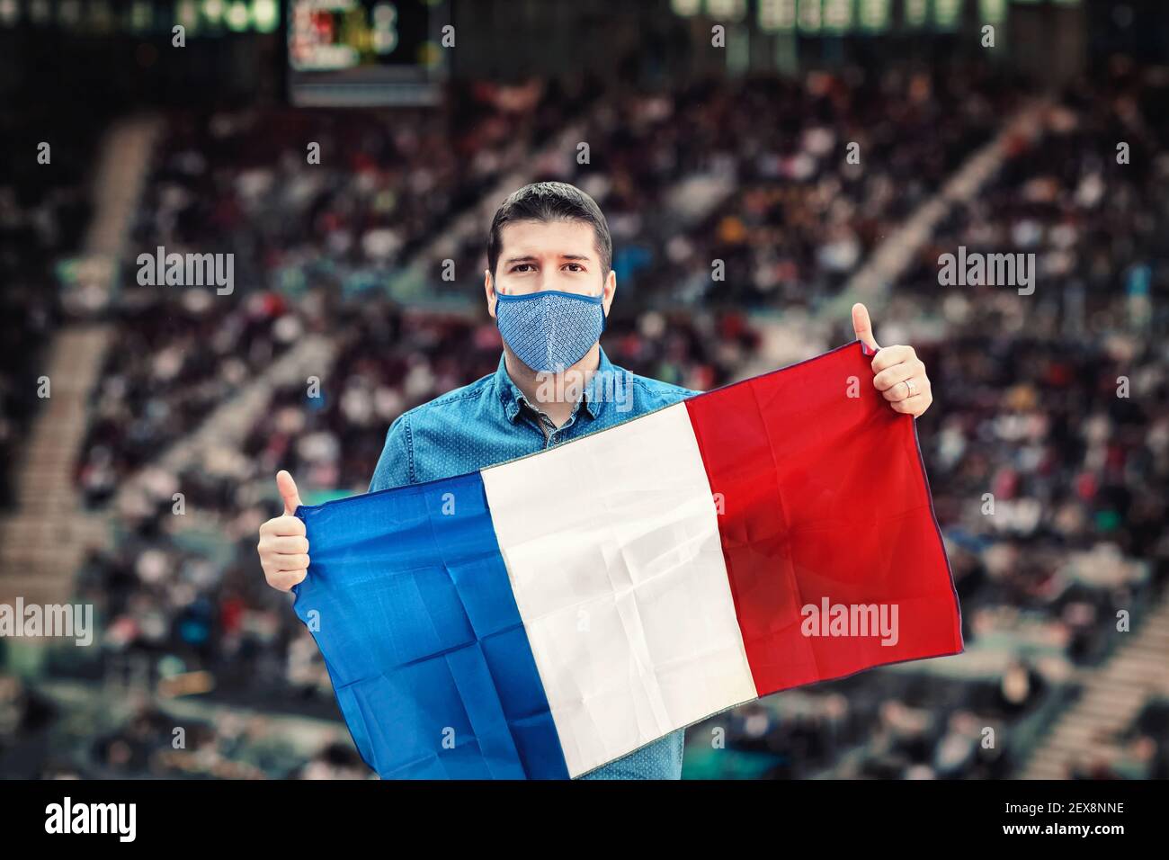 Happy supporter holding national flag of France cheering his favorite team at international sport event at stadium Stock Photo