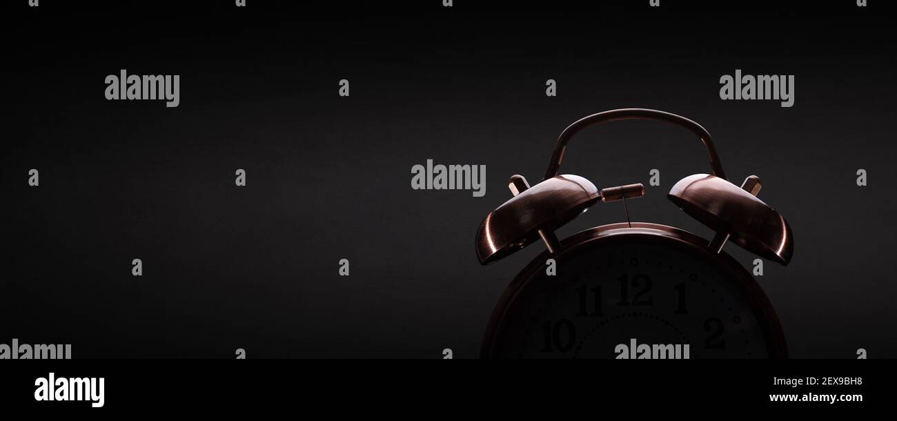 Retro alarm clock on dark background with subtle lighting Stock Photo