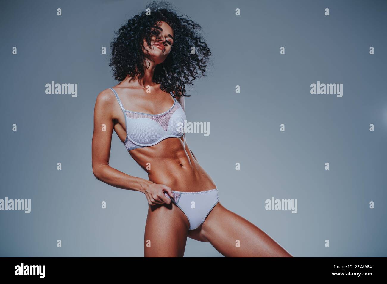Young slim woman in sports lingerie on gray wall background Stock Photo
