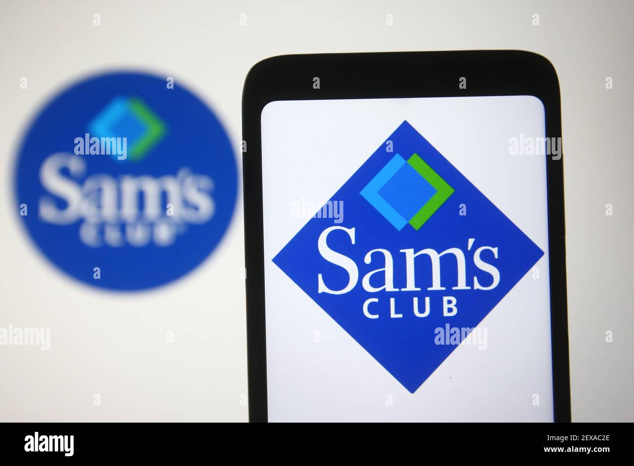 In this photo illustration a Sam's Club logo of a US chain of membership-only retail warehouse clubs is seen on a smartphone and a pc screen. Stock Photo