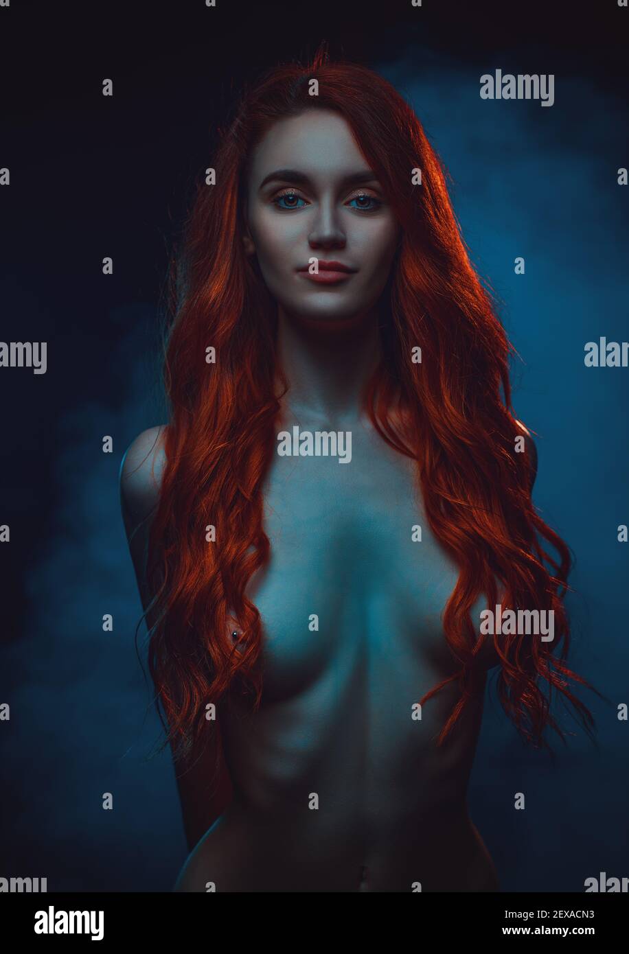 Young slim nude woman with red hair portrait in dark colors with smoke Stock Photo