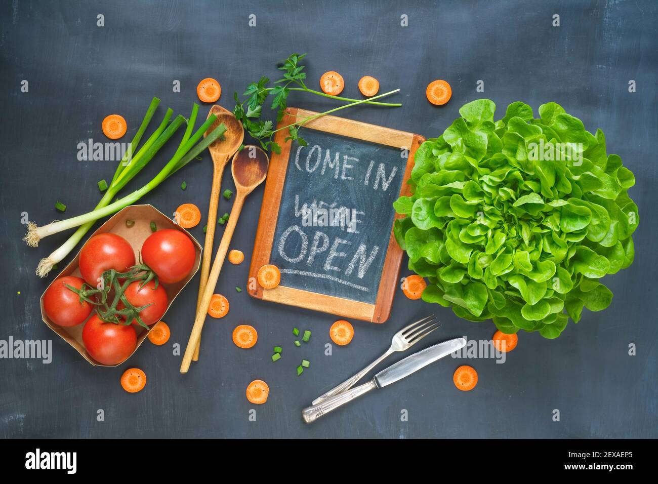 reopen sign, restaurant ready to service after corona lockdown, food ingrdients kitchen utensils and message on blackboard,flat lay Stock Photo