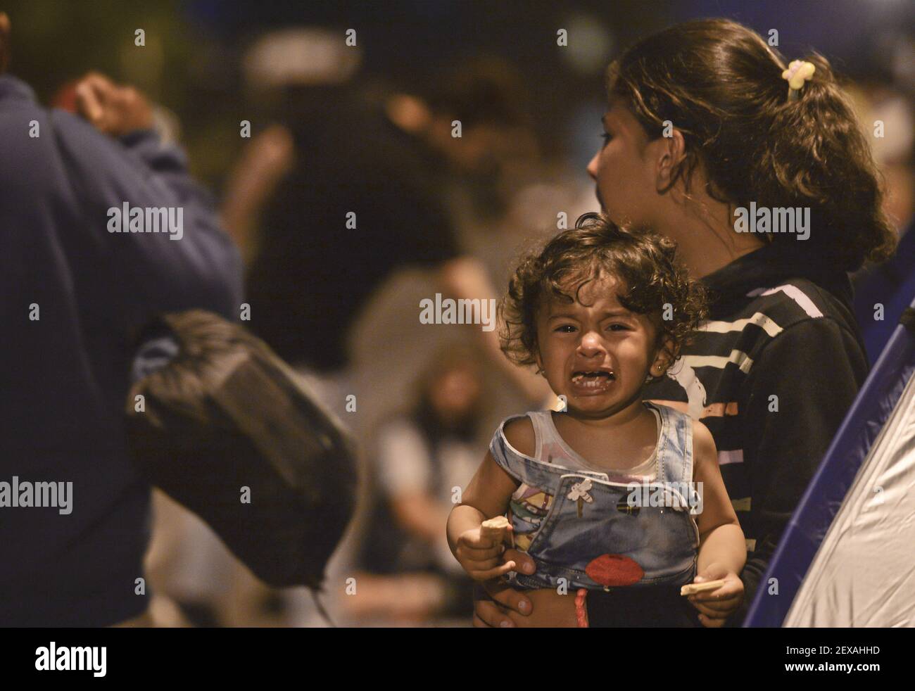 A migrant holding a crying child near the gates at the Serbia-Hungary border in Horgos, Serbia, on September 16, 2015. (Photo by Artur Widak) *** Please Use Credit from Credit Field *** Stock Photo