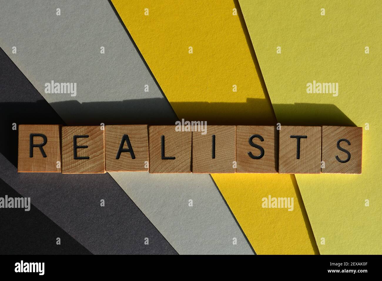 Realists, word in wooden alphabet letters isolated on yellow and grey background Stock Photo