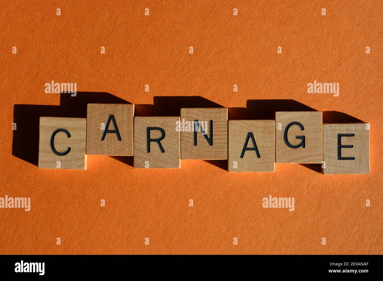 Carnage, word in wooden alphabet letters isolated on orange background as banner headline Stock Photo
