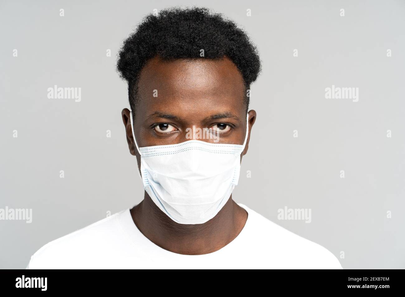 African American young man wearing face medical mask, looking at camera, isolated on grey background Stock Photo