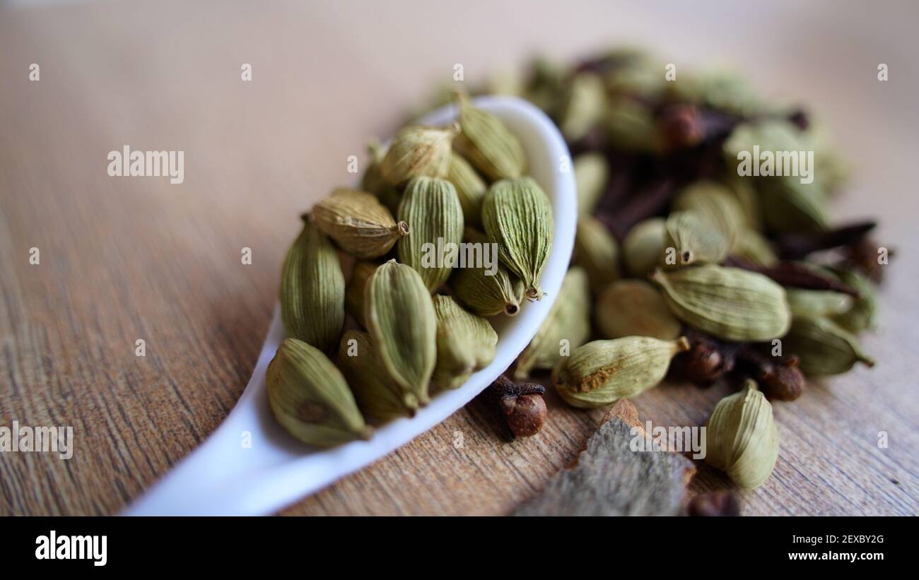 Green cardamom pods on rustic wooden background. Indian spices macro view. elaichi (Elettaria cardamomum) Stock Photo
