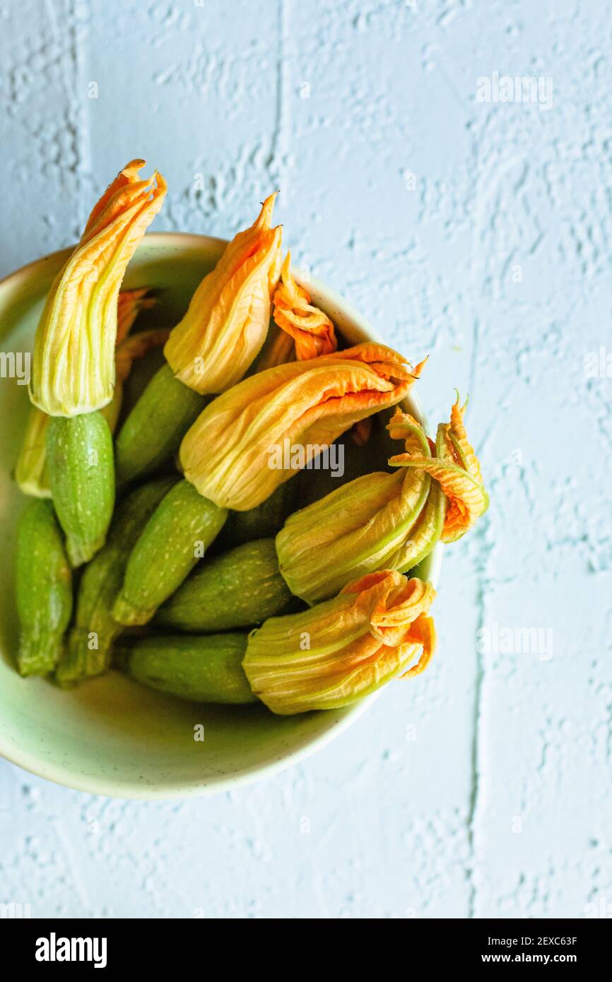 Fresh zucchini flowers with attached baby zucchini in a pastel green