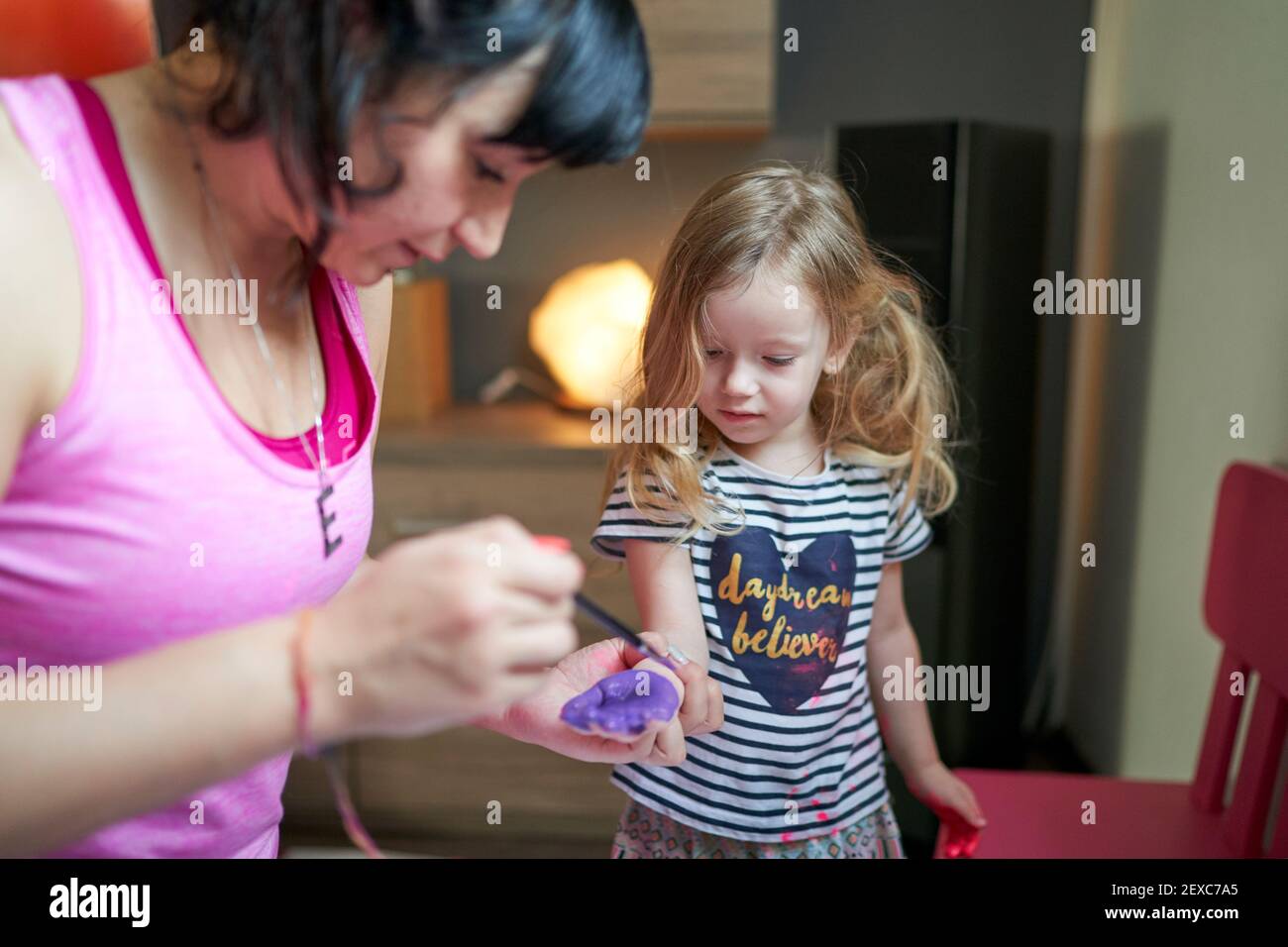 Mother painting on daughter's palms with watercolours Stock Photo