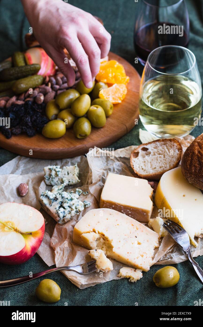 A hand reaching for food in a cheese board spread Stock Photo