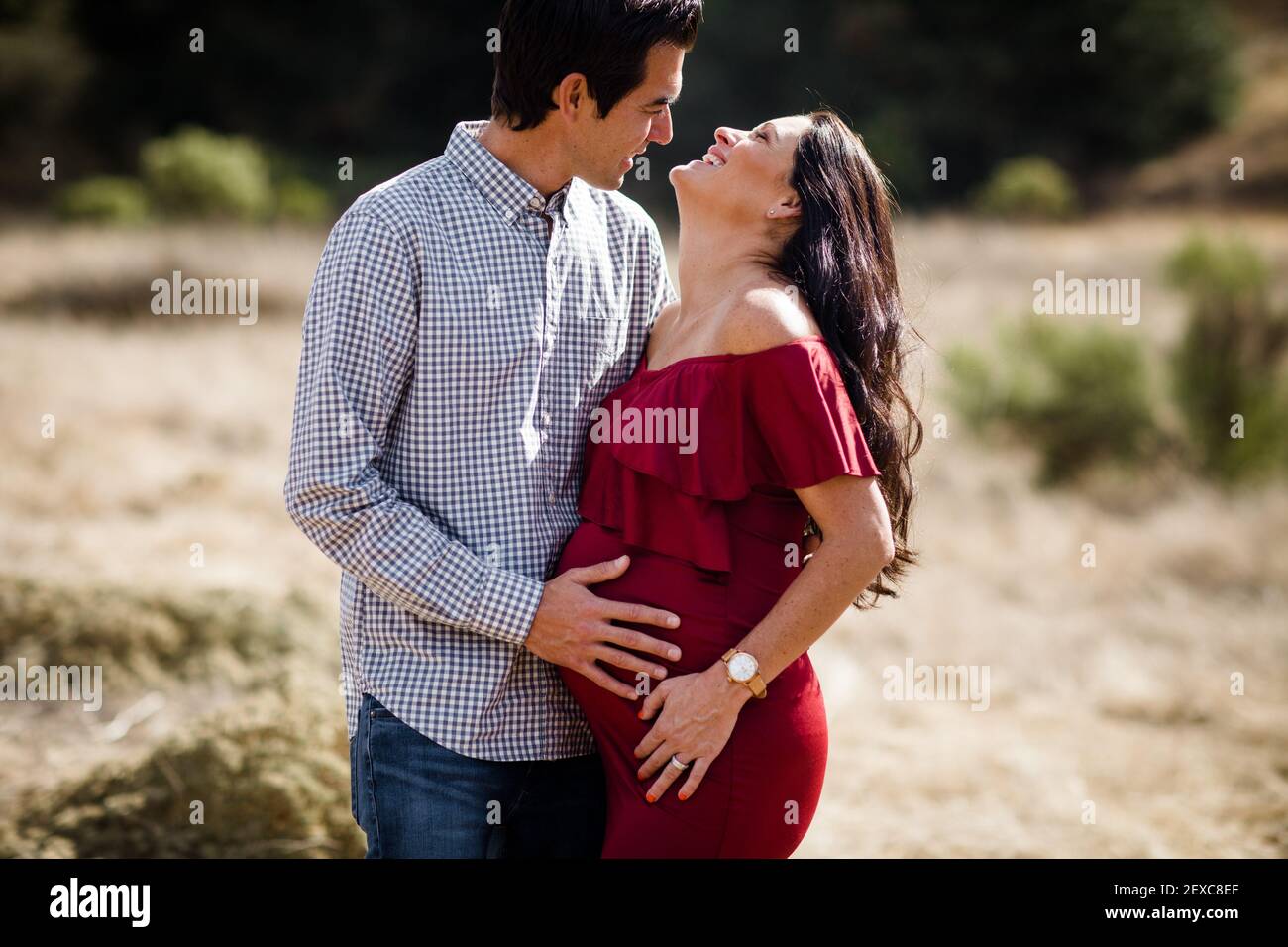 Husband and Expectant Wife Posing in Field in San Diego Stock Photo