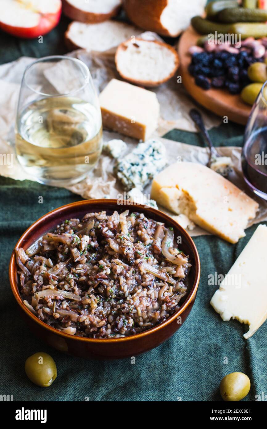 Wild rice salad surrounded by cheese board condiments and wine Stock Photo