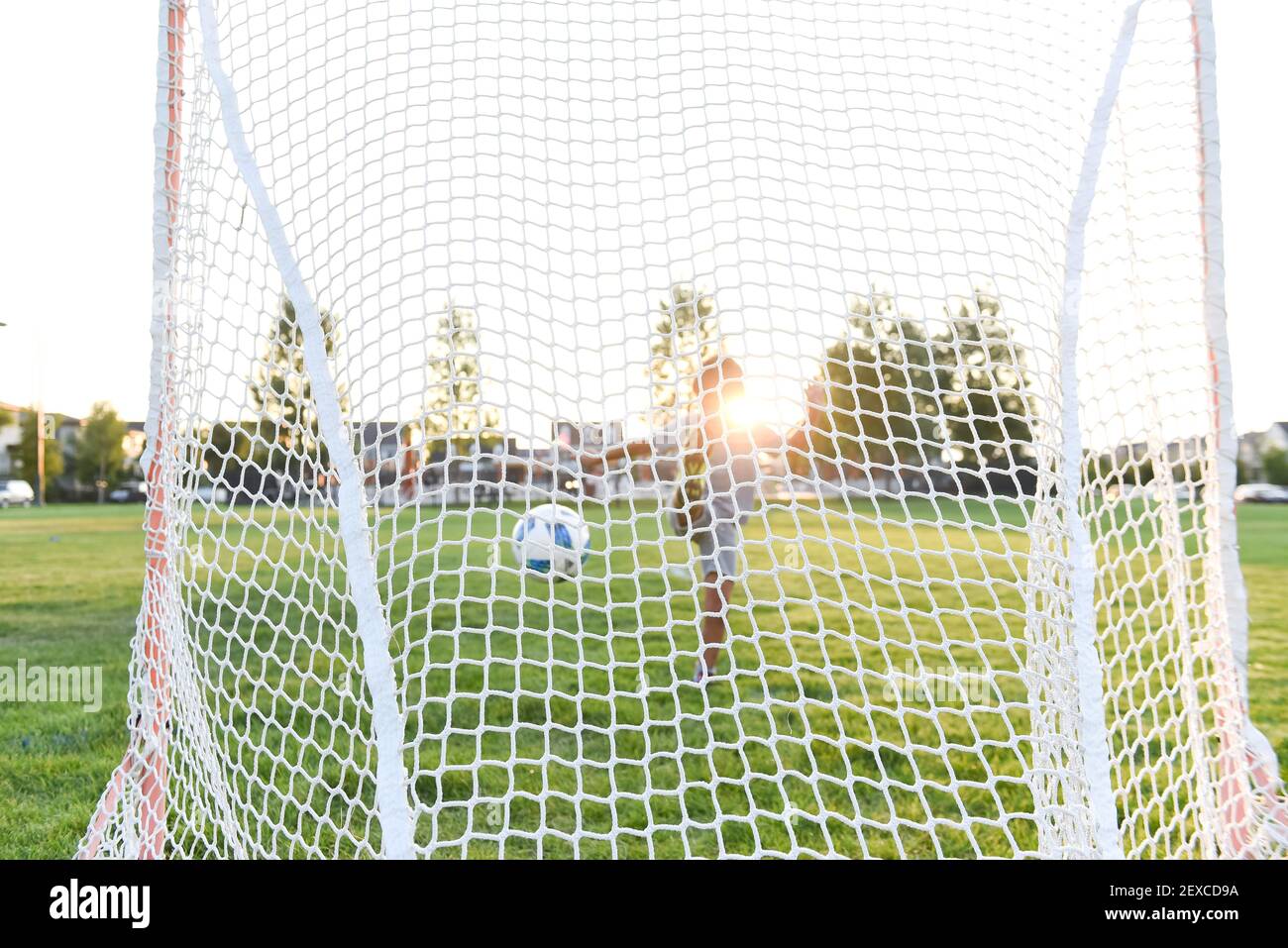 A soccer ball in mid-air after a young boy kicks the ball into the net Stock Photo