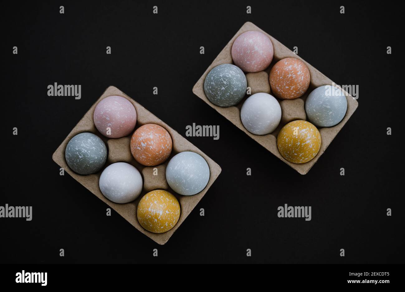 Overhead view of colorful Easter eggs in egg carton on black Stock Photo
