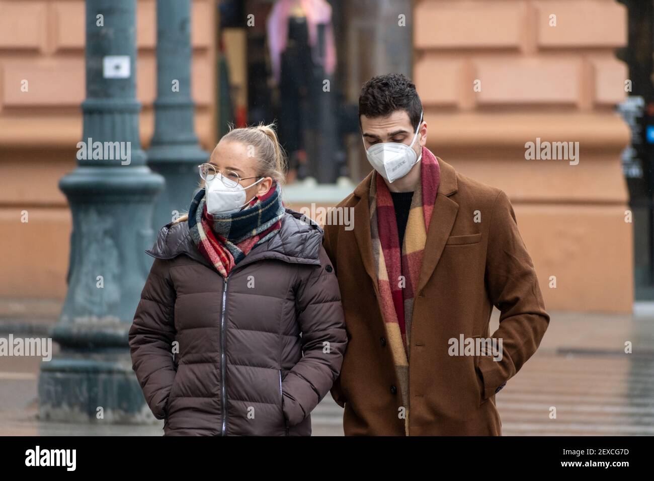 Beautiful young couple wearing mask and walking together in the city during Covid or Coronavirus outbreak Stock Photo