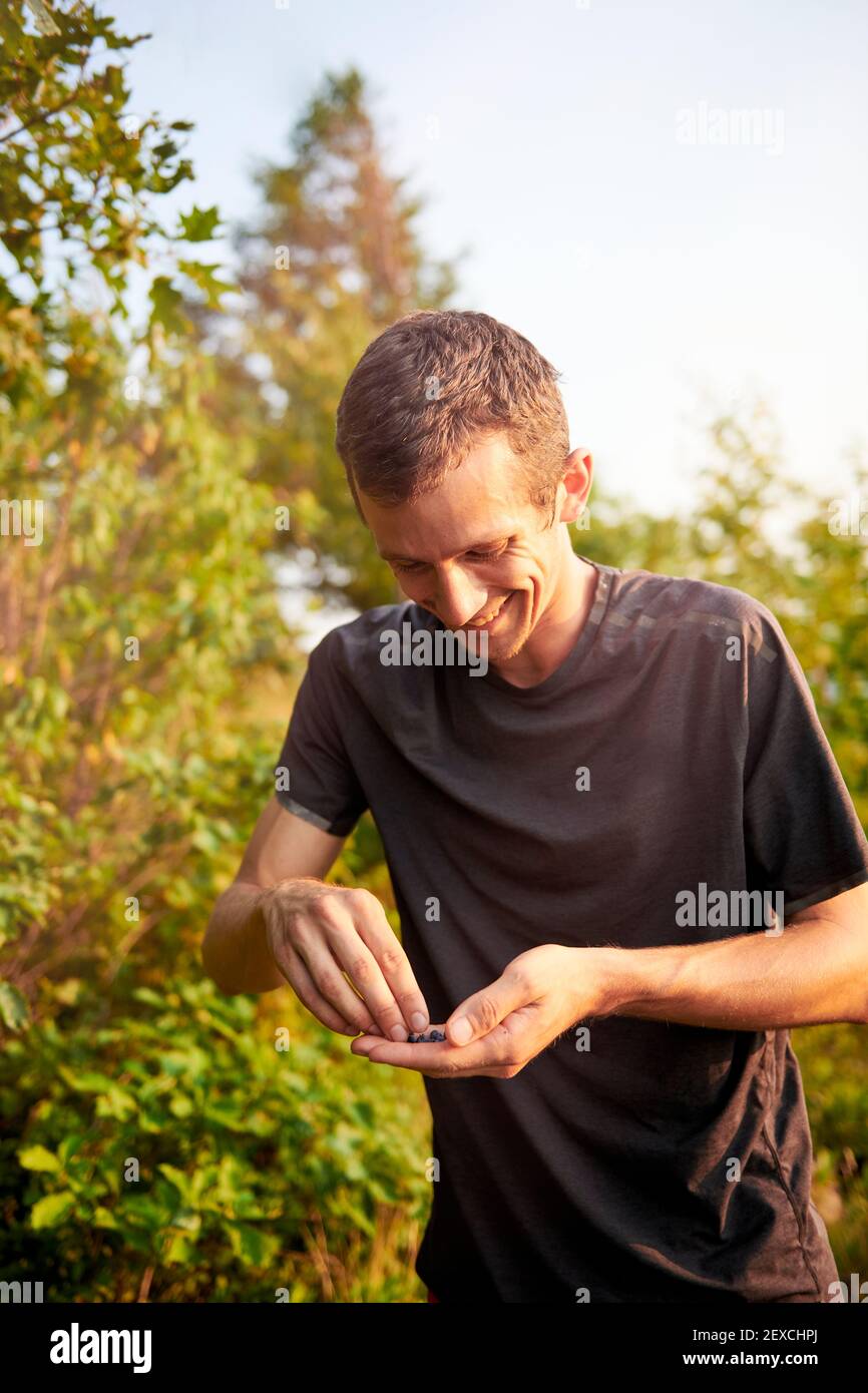Adult male trail runner on a mountain ridge snacking on blueberries Stock Photo