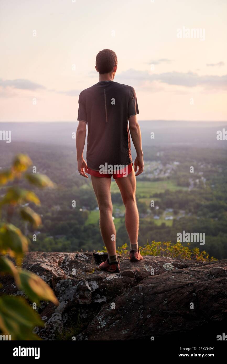 Adult male trail runner climbing on a mountain ridge at sunset Stock Photo