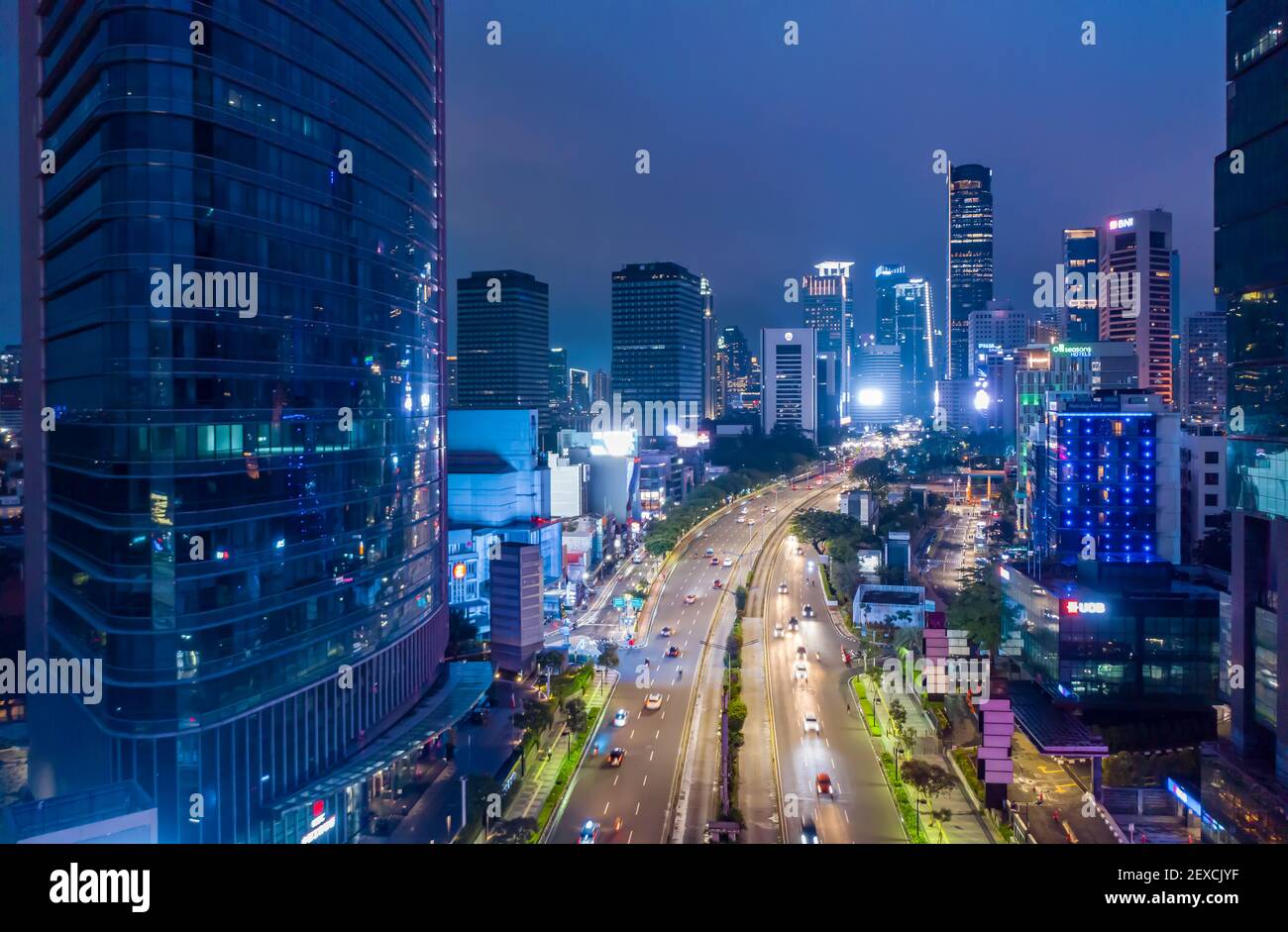 Aerial night view of the traffic on the multi lane highway through modern city center with skyscrapers Downtown Jakarta urban city center Stock Photo