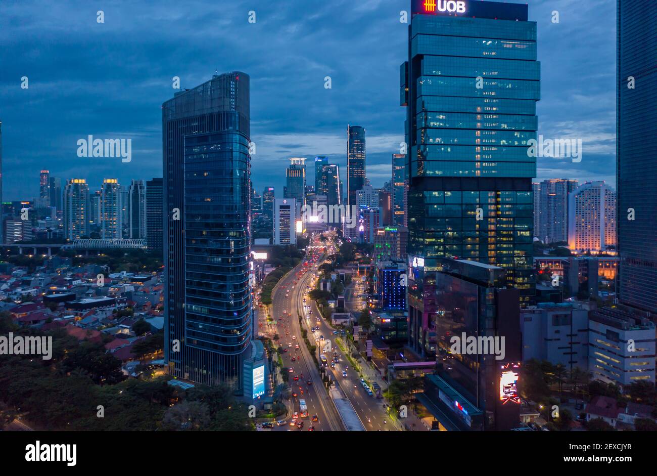 Aerial view of multi lane highway through modern city center with tall skyscrapers in blue evening light Night time traffic through downtown Jakarta, Indonesia Stock Photo