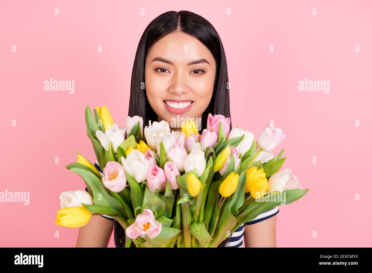 Photo portrait of asian girl smiling keeping fresh flowers bouquet in spring isolated pastel pink color background Stock Photo