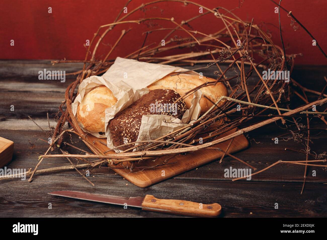 https://c8.alamy.com/comp/2EXD0JK/a-loaf-of-fresh-bread-flour-product-in-a-birds-nest-on-a-wooden-table-on-a-red-background-2EXD0JK.jpg