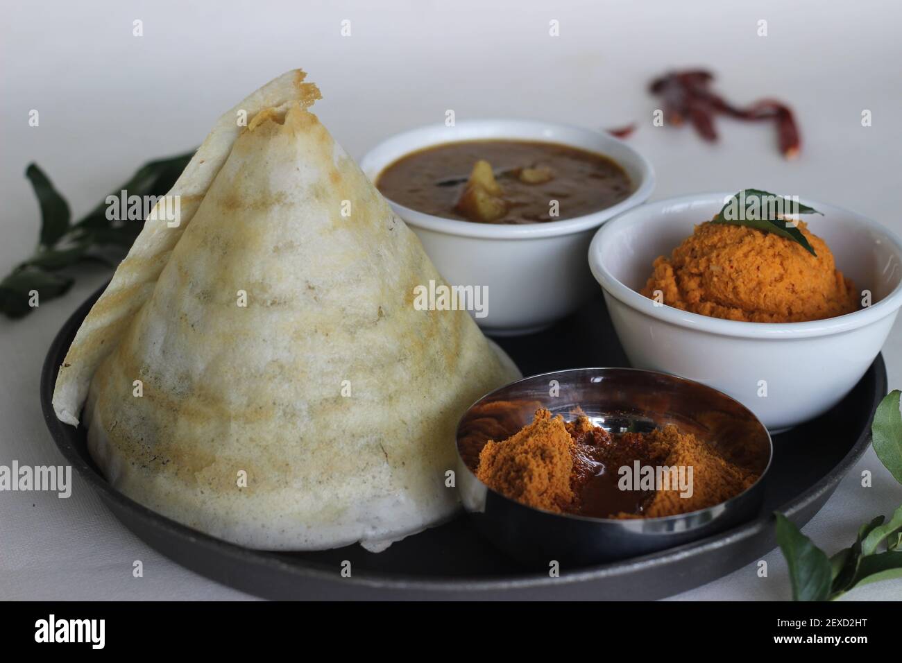 Crispy thin ghee dosa with sambar, coconut chutney and Molaha Podi. Dosa is served in tent shape. A South Indian breakfast. Shot on white background Stock Photo