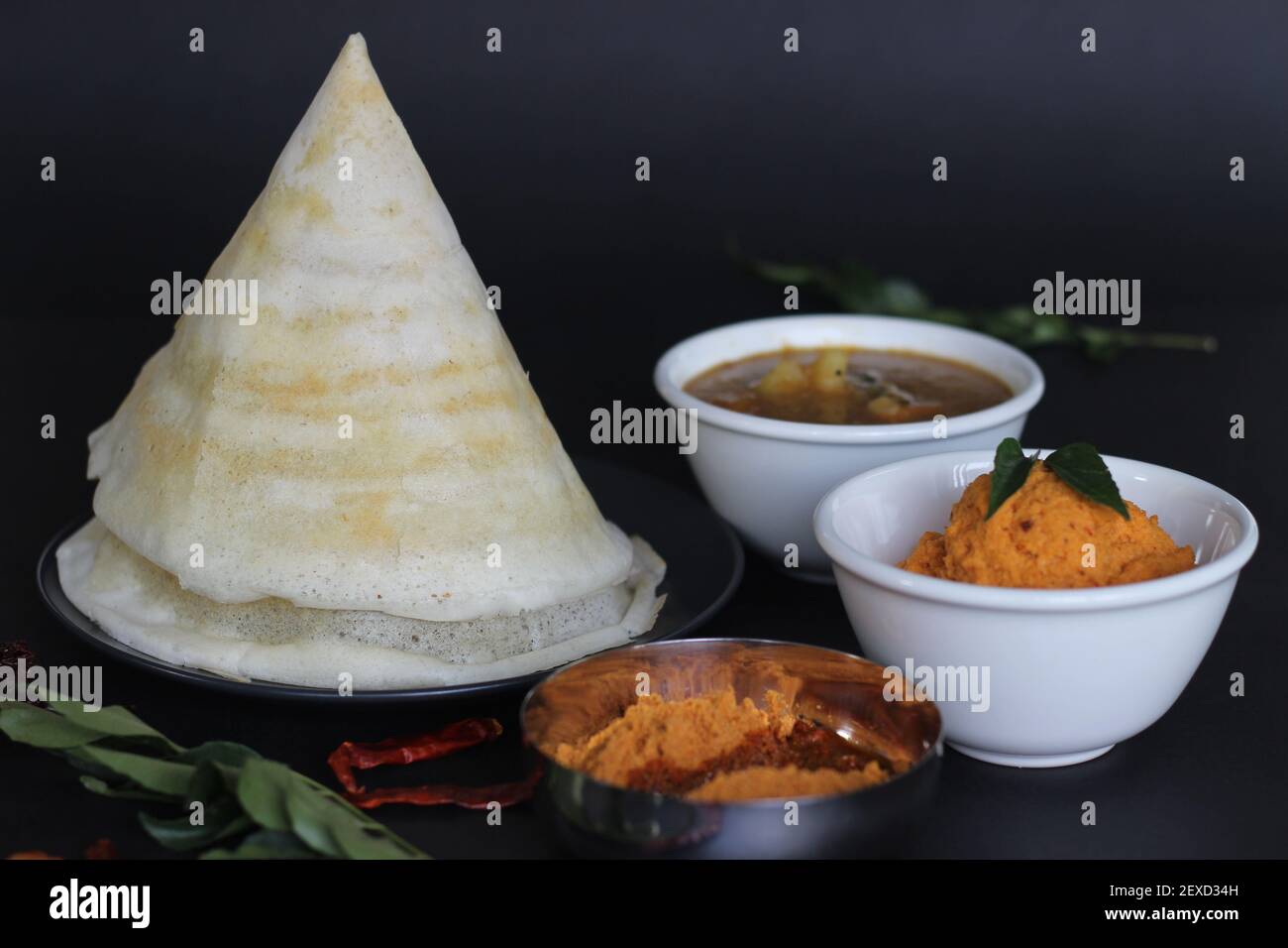Crispy thin ghee dosa with sambar, coconut chutney and Molaha Podi. Dosa is served in tent shape. A South Indian breakfast. Shot on black background Stock Photo