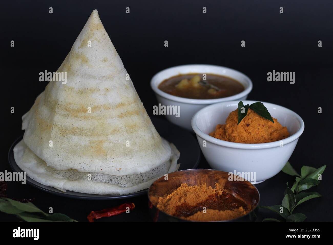 Crispy thin ghee dosa with sambar, coconut chutney and Molaha Podi. Dosa is served in tent shape. A South Indian breakfast. Shot on black background Stock Photo