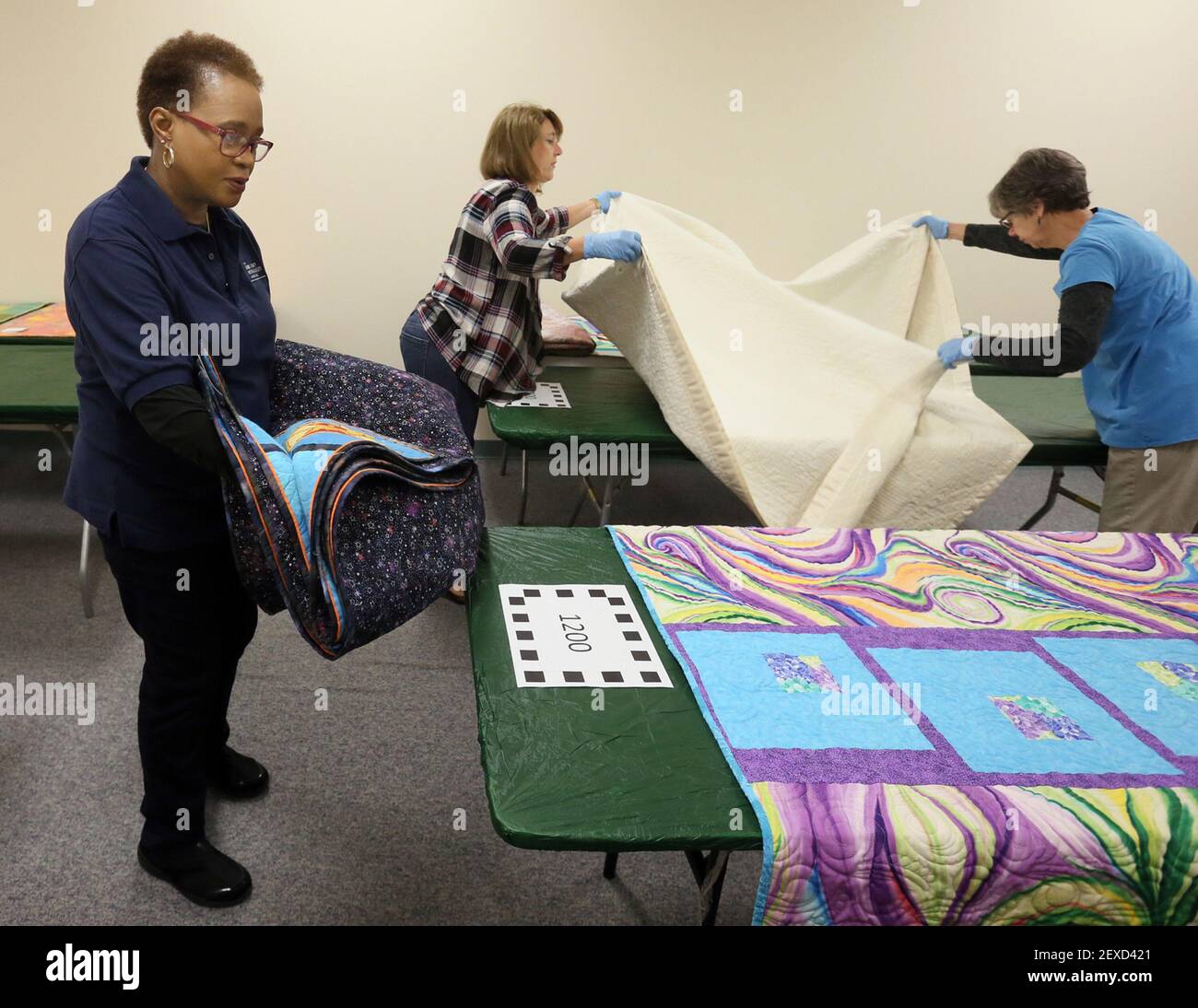 Volunteers Tanya Robinson, left, Debbie Shives and Joanna Mack sort through quilts at the Mutton