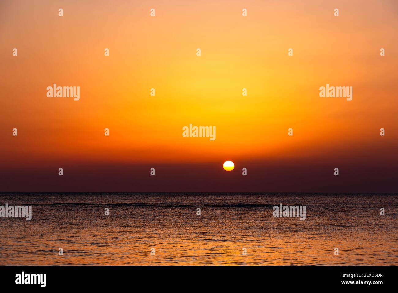 Bright sunset with a big yellow sun under the sea surface. Stock Photo