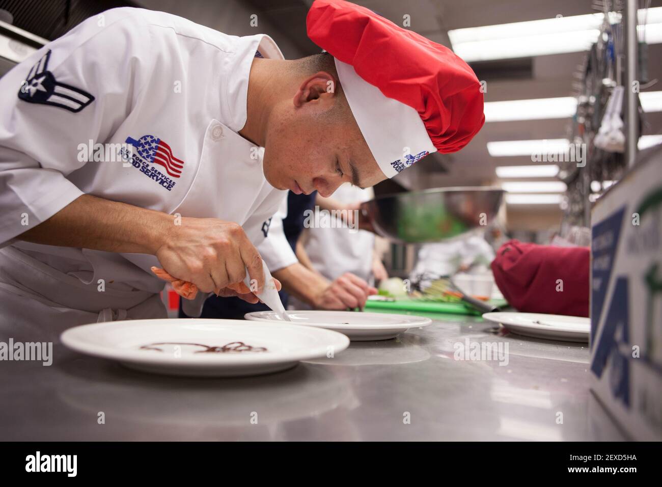 Airman 1st Class Ruel Abastas, a 90th Force Support Squadron chef, decorates a plate with chocolate syrup for a dessert dish during an 'Iron Chef' competition at the Chadwell Dining Facility on F.E. Warren Air Force Base, Wyo., Aug. 27, 2015. Chefs from the 90th FSS had to create an entree incorporating the secret ingredient, cheese crackers with peanut butter, along with a dessert dish within the hour time limit. (Photo by Lan Kim/U.S. Air Force) *** Please Use Credit from Credit Field *** Stock Photo