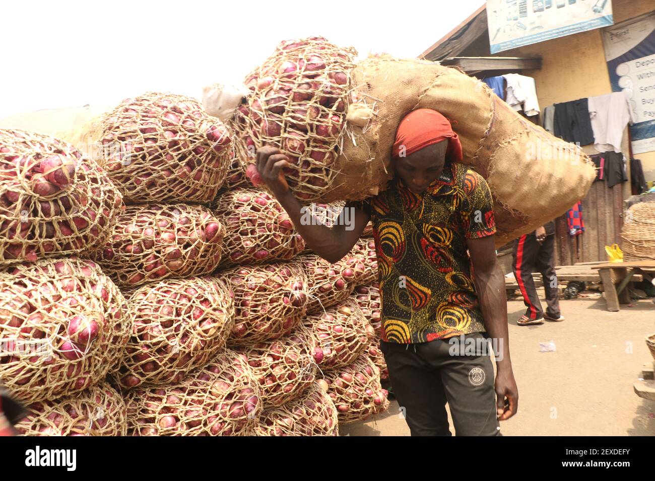 A labourer lifts a bag of onions at the Lagos food market in Mile12