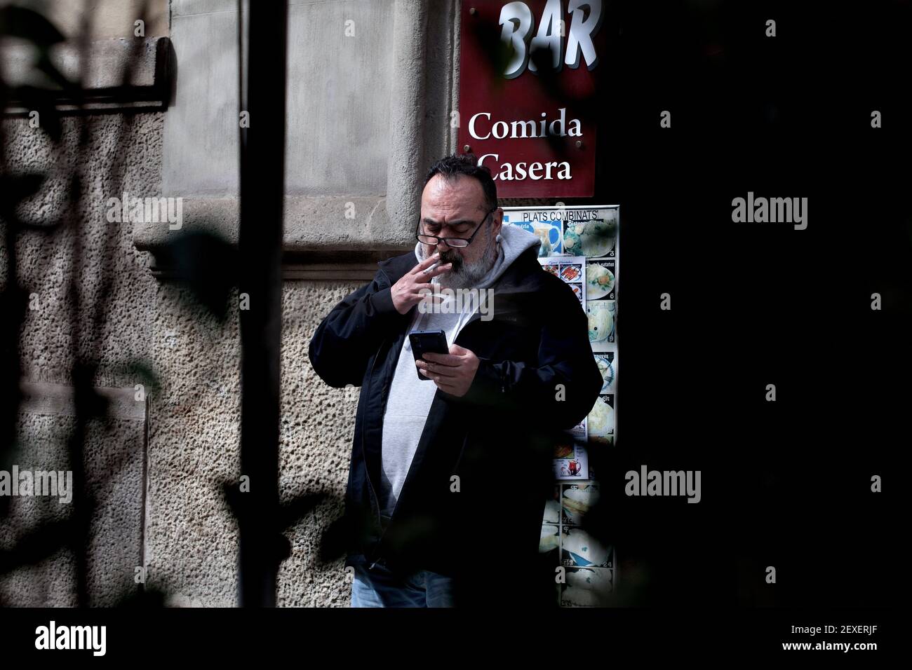 Man smoking and looking at his mobile phone, Barcelona, Spain. Stock Photo