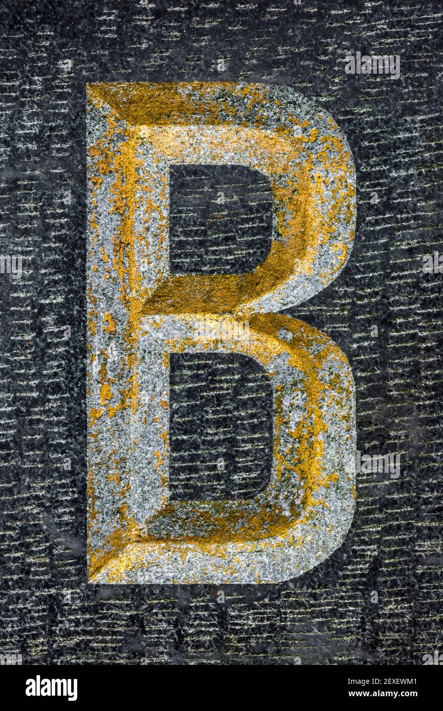 Golden weathered letter B on black granite Stock Photo