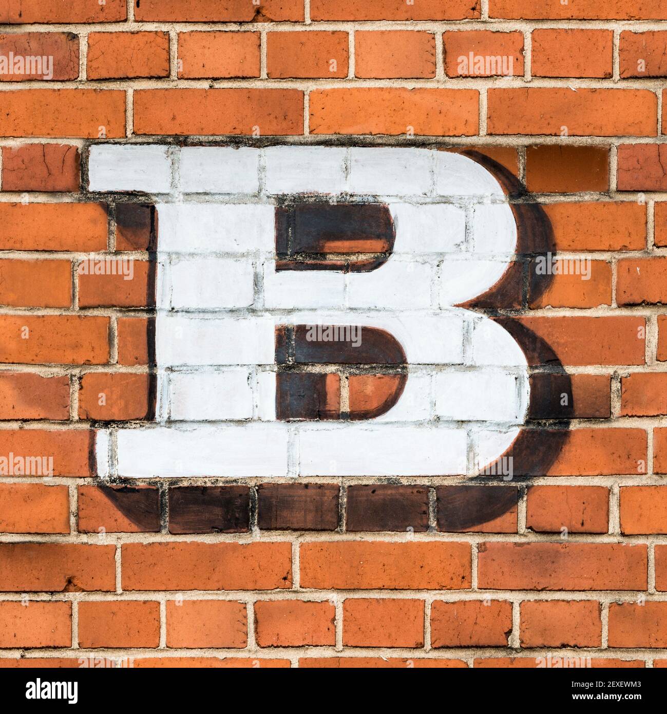 A white capital letter B painted on a red brick wall Stock Photo
