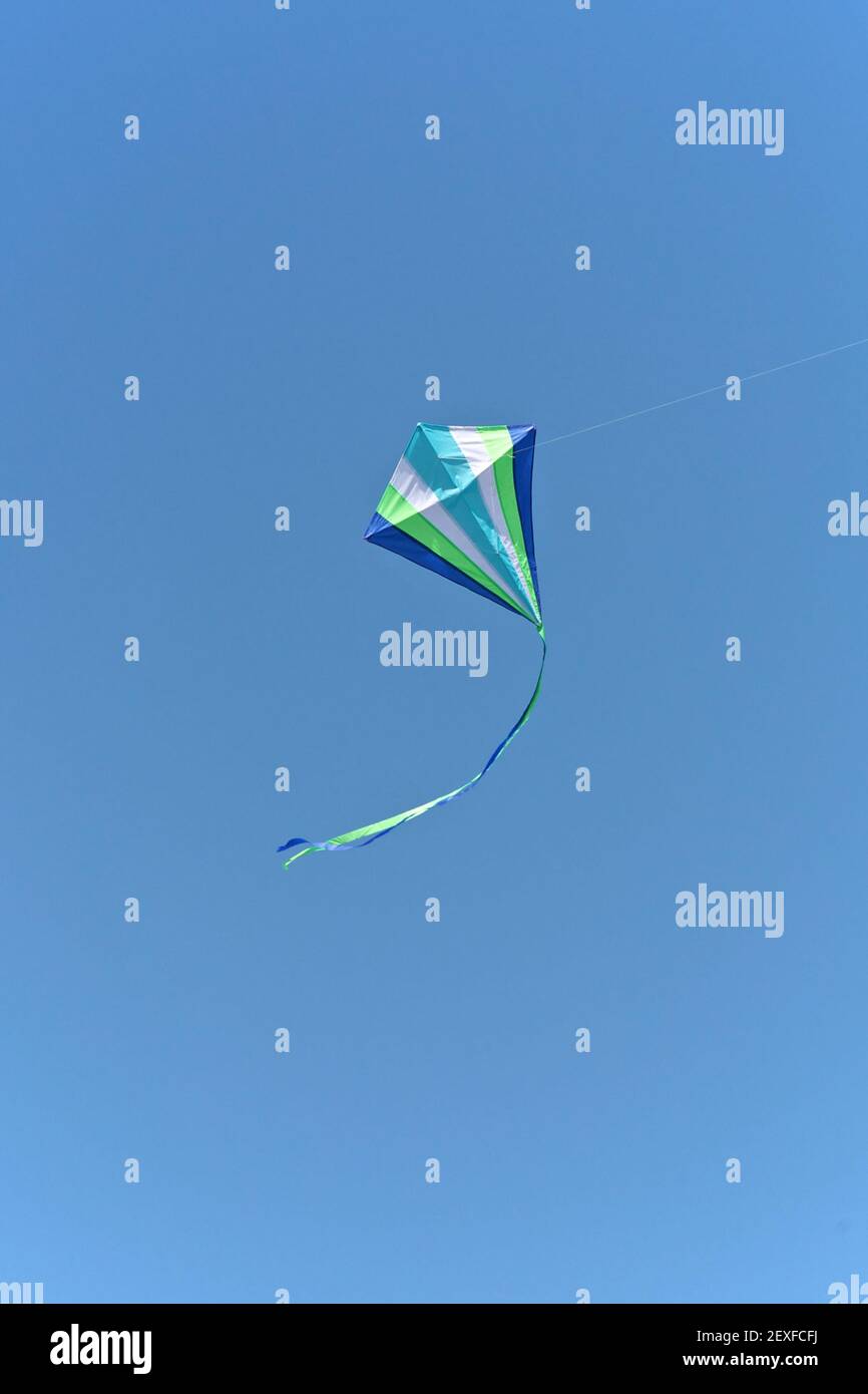 Flying white kite in blue sky with clouds hires stock photography and