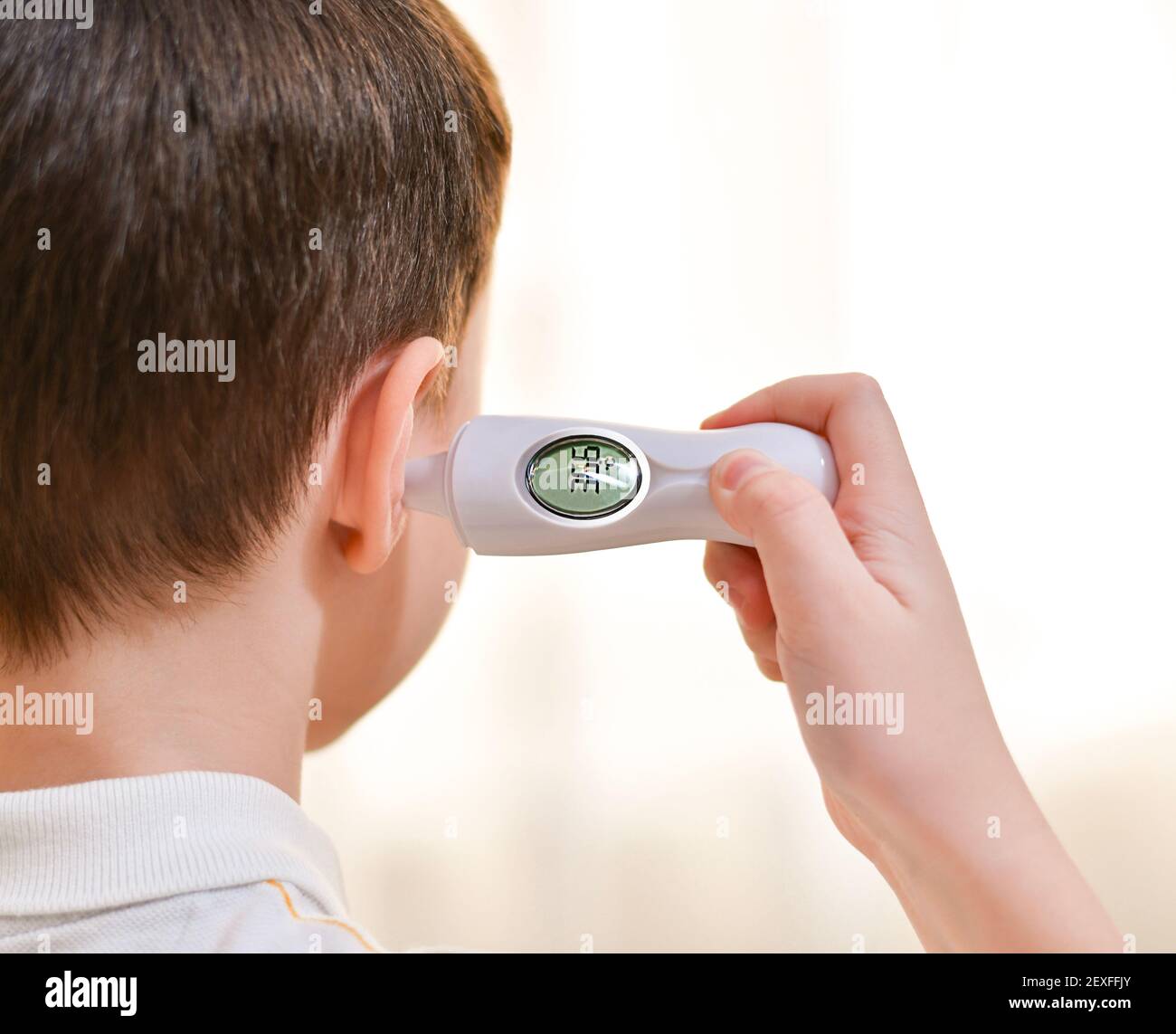 Measuring the temperature with an infrared earpiece for a child. Indicators on display 36.6, version of the norm. Stock Photo